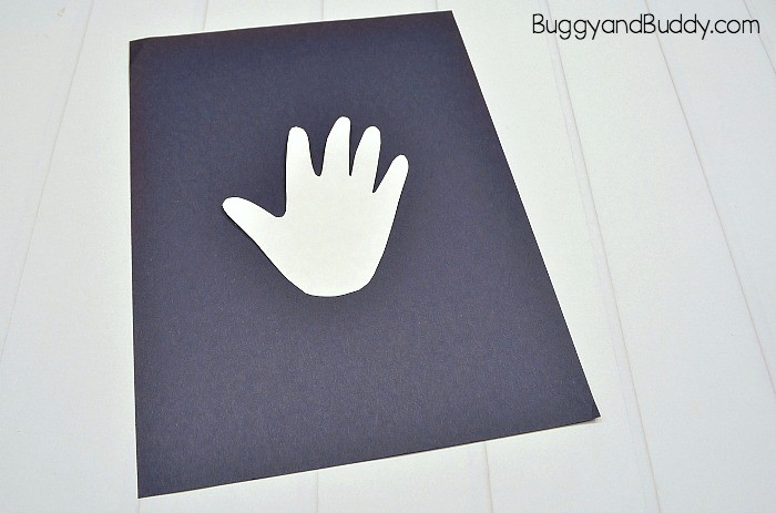 tape your cut out handprint to the black paper